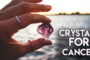 A Woman Holding A Small Crystal Representing Crystal For Cancer Patients.