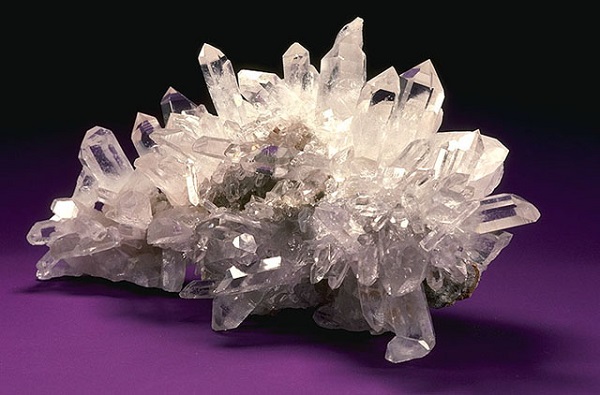 A Large Cluster of Ameythyst Crystal Placed On A Table.