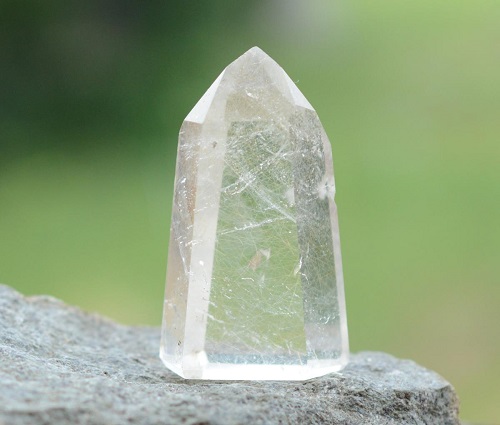 A White Transparant Crystal Stone Placed On A Rock.