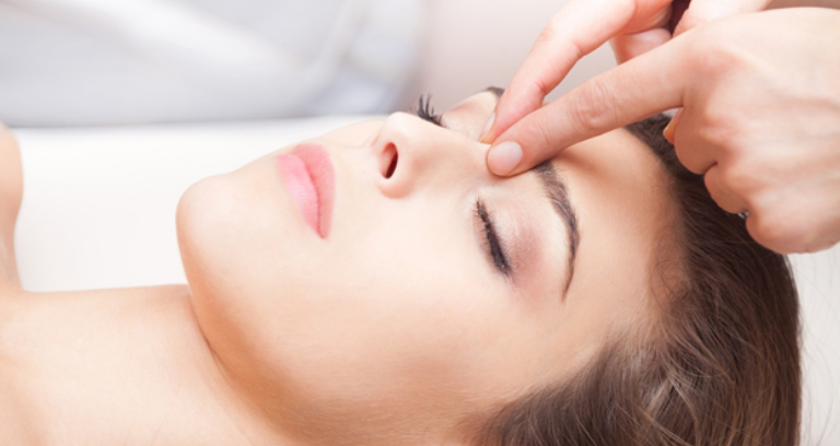 A Young Woman Taking Face Massage From A Therapist.