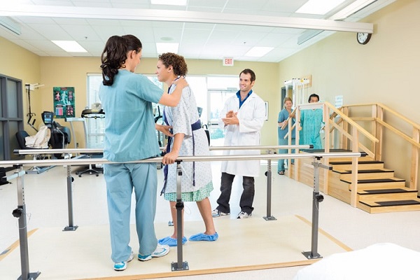 Rehabilitation Therapist Supports A Young Girl On Treadmill In Physiotherapy.