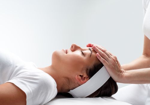 A peaceful Young Woman Taking Reiki Healing On Her head.