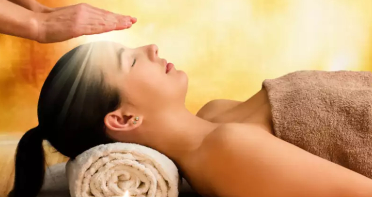 Midsection of therapist performing reiki treatment on woman at spa