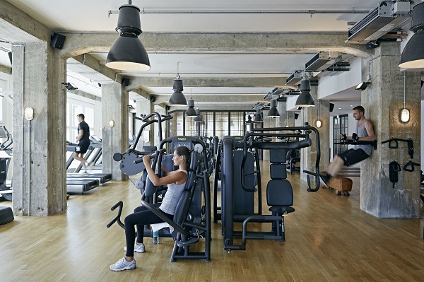 3 people doing various kinds of exercises inside a fitness center.